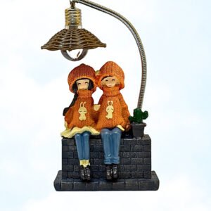 Adorable figurine of two kids in matching sweaters sitting under a lamp, sharing a cute cozy moment